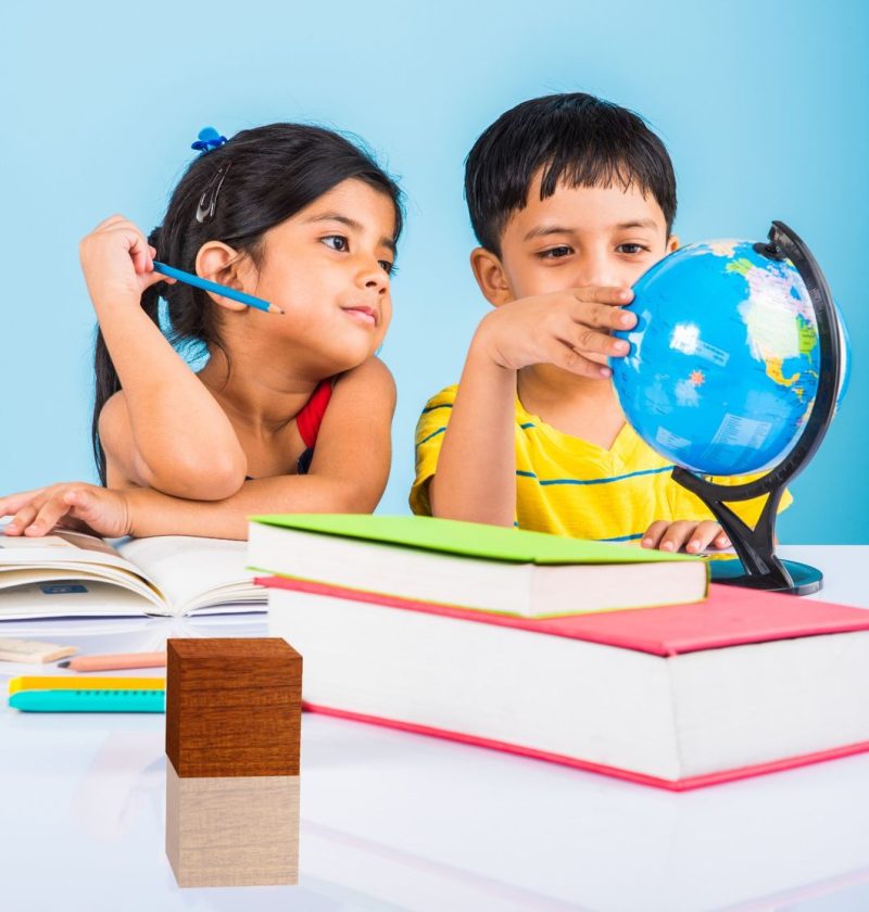 cute-little-indian-asian-kids-studying-study-table-with-pile-books-educational-globe-isolated-light-blue-colour